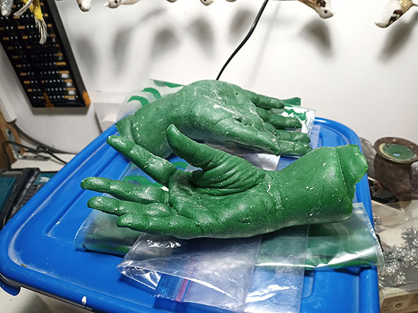 Two different casts of Emma's hand, both in green but in different poses