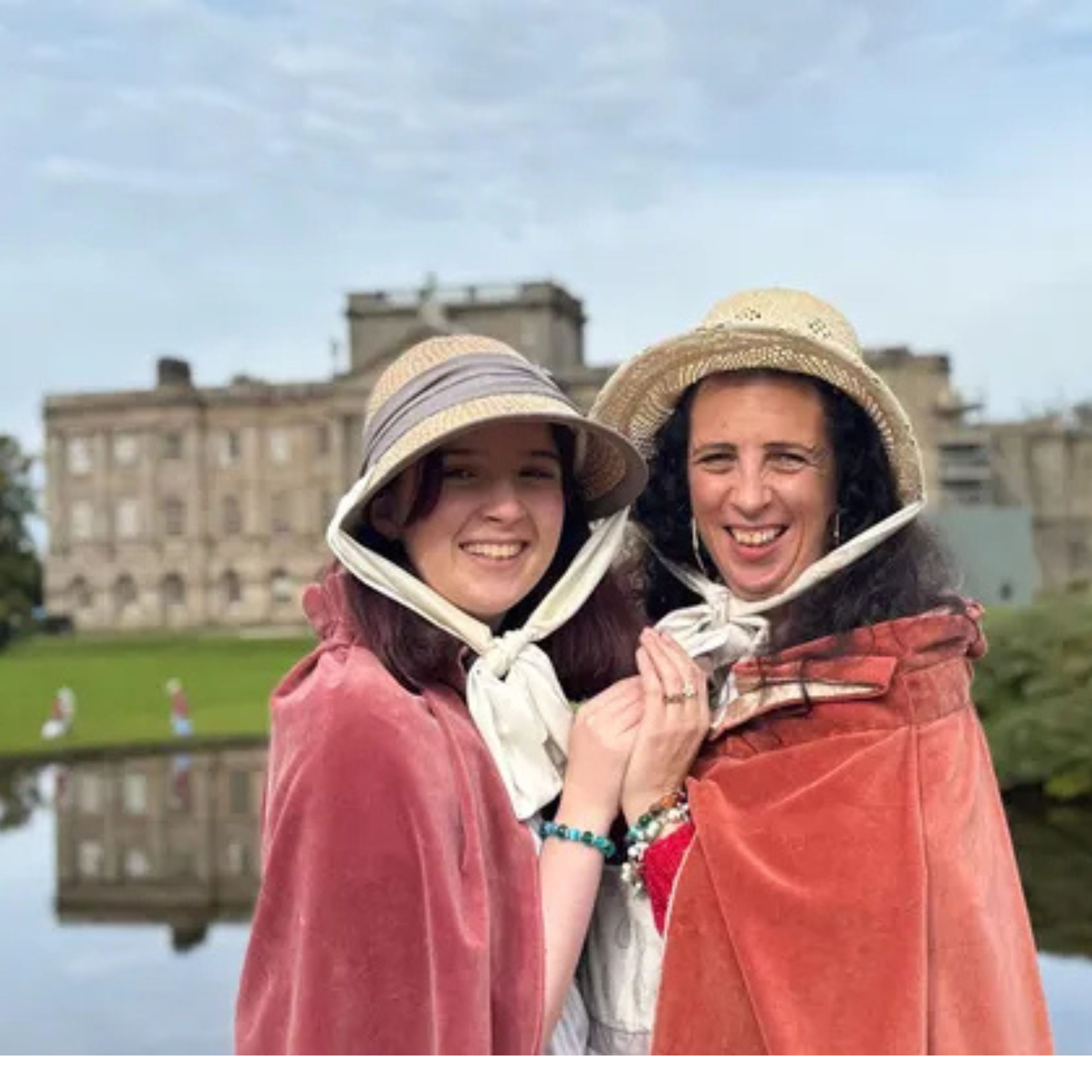 Two women, a mother and daughter wearing bonnets and capes, dressed up as Georgian ladies at a stately home