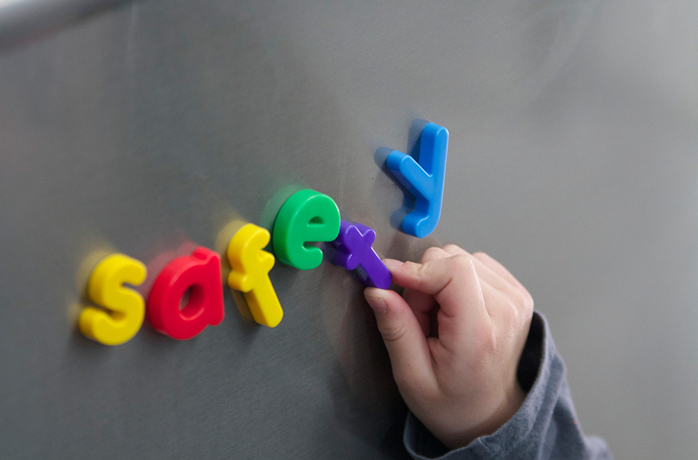 child spelling safety with fridge magnets