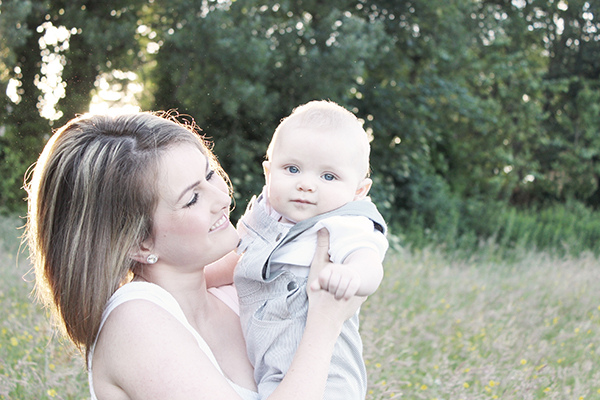 Young mum Chantel is smiling and holding up up baby Oliver to her face