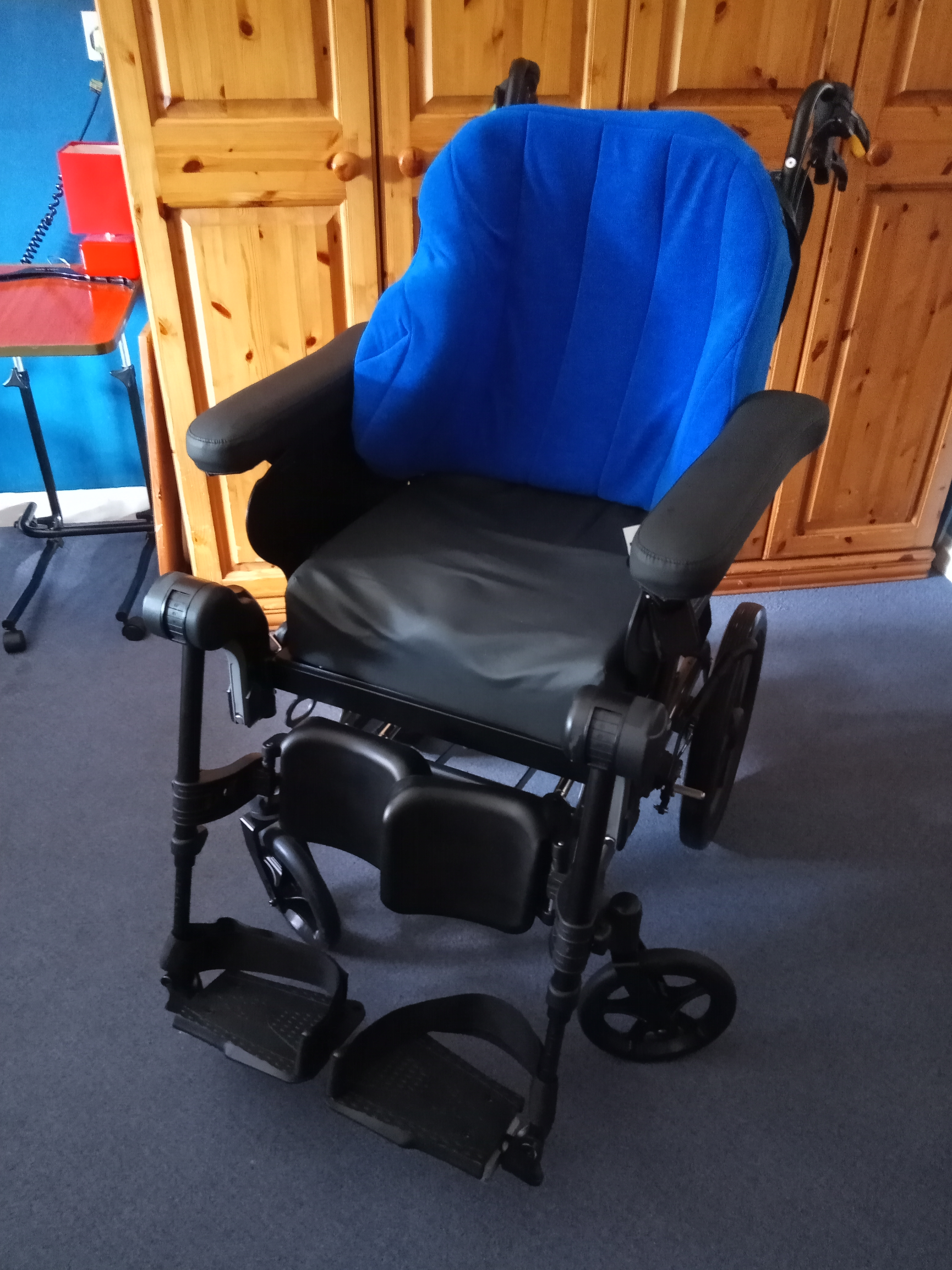 A blue wheelchair in front of a wooden wardrobe