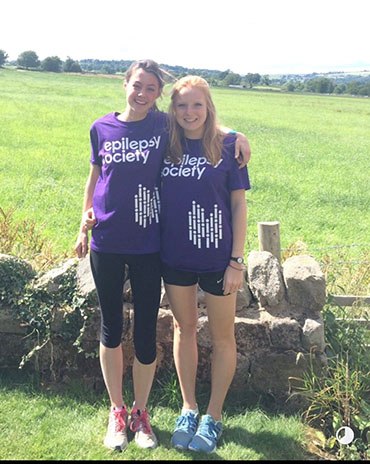 Julia and Imy are both wearing Epilepsy society t-shirts and taking a break while out for a run in the countryside