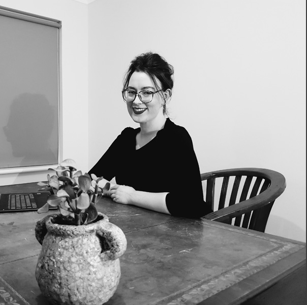 black and white image of a smiling dark haired woman at a table.