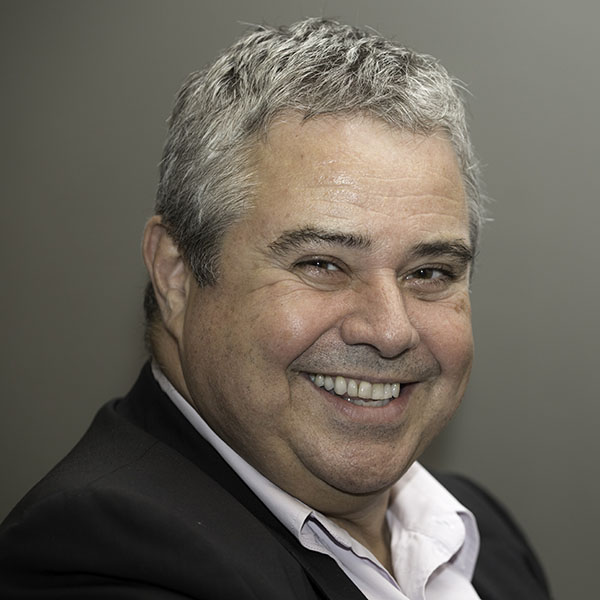 Professor Ley Sander is sideways to the camera and smiling. He is wearing a dark suit and has white hair