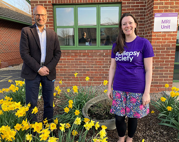 Sarah and Professor Sanjay Sisodiya are standing amid the daffodils outside the MRI unit