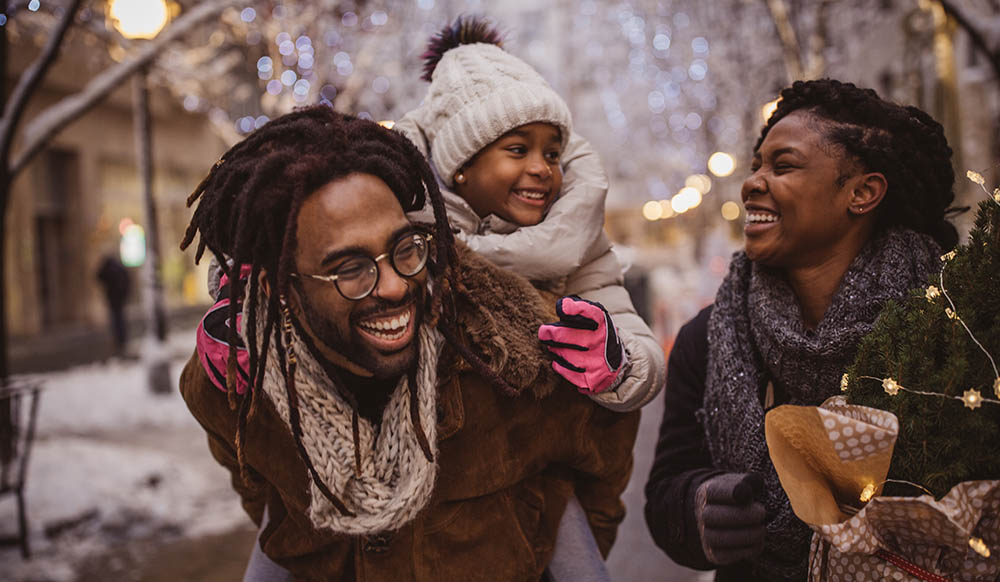 Christmas image of 2 adults and a small child walking through snow