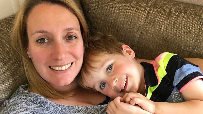 Woman and boy lying on a sofa smiling at the camera