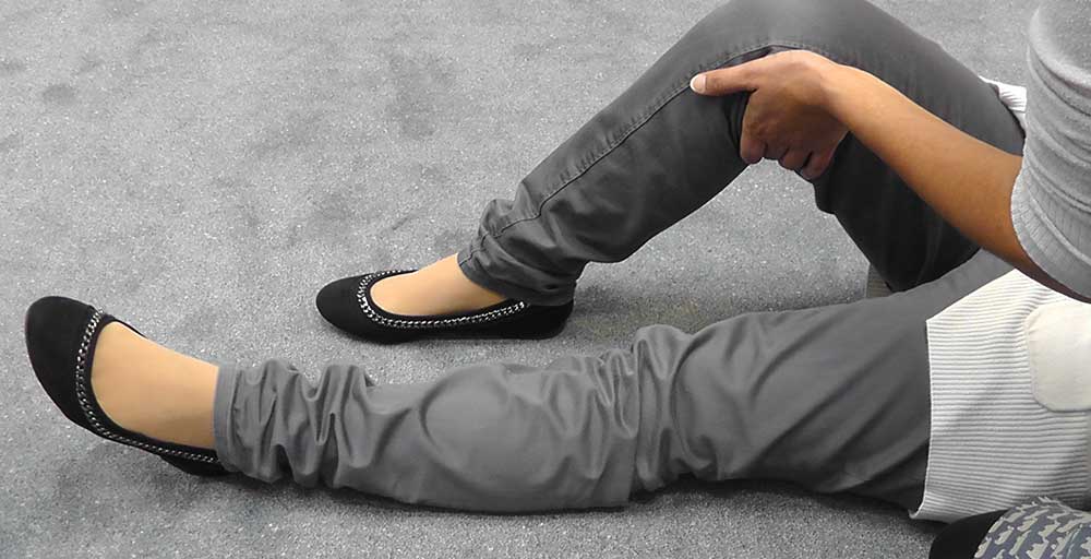 Use your other arm to reach across to the person’s knee that is furthest from you, and pull it up so that their leg is bent and their foot is flat on the floor.