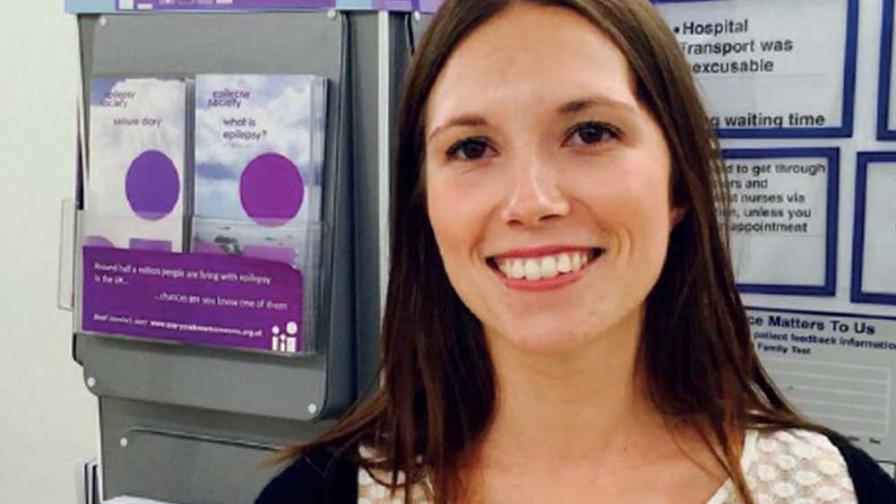 Jasmine smiling in front of our epilepsy information leaflets