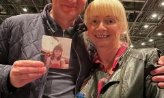 Shirley and Neil are at a concert, holding a photo of Fay.