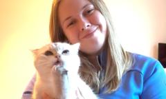 Woman with fair shoulder length hair holding a white cat