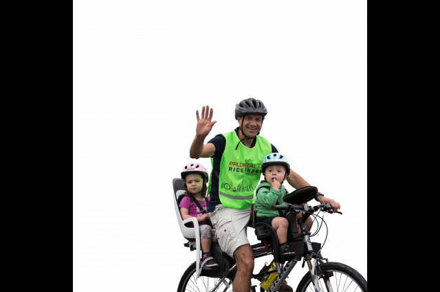 A father riding a bike with his kids smiling and waving