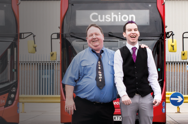Two of our supporters standing in front of some double decker buses